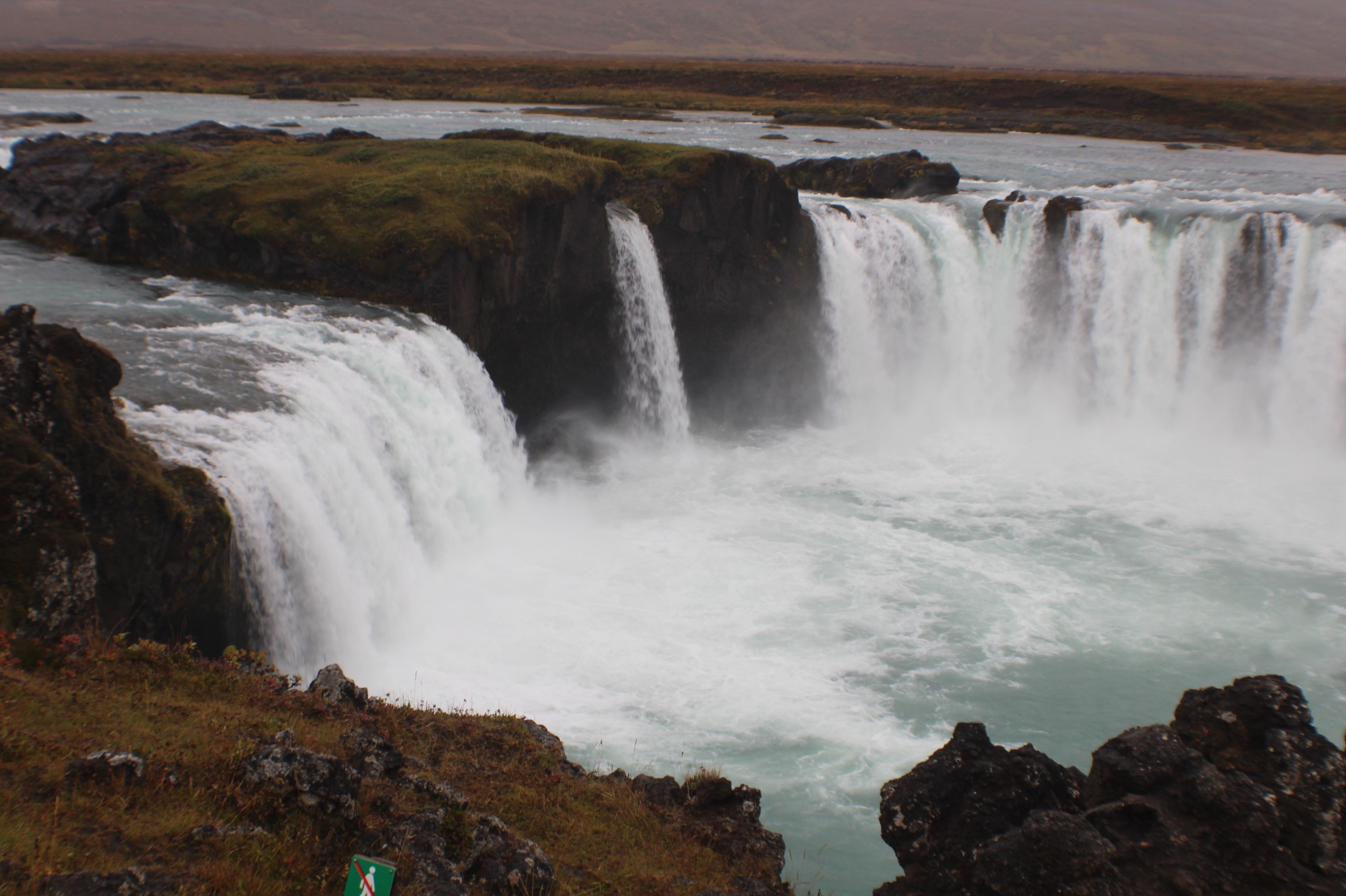 A broad waterfall pouring over dark rock in Iceland.