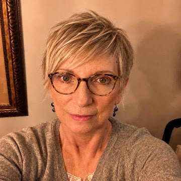 Janet Nash, wearing glasses and a gray cardigan.